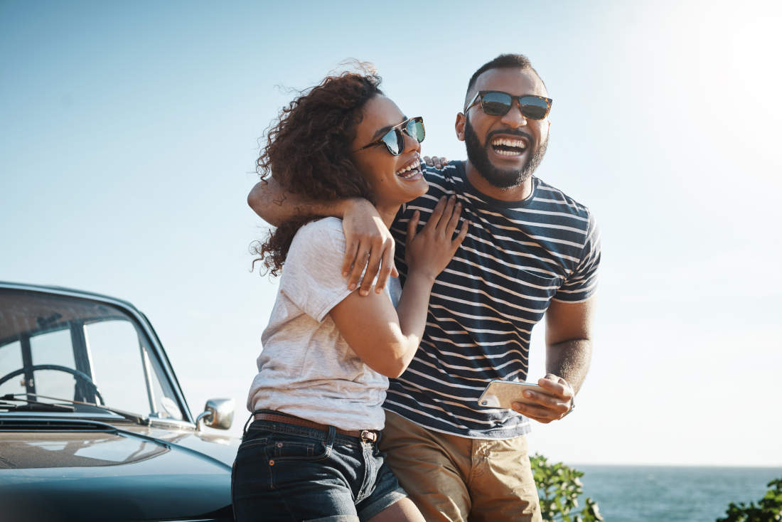 Couple hugging leaning against a hood of car.